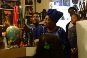 Michele Tingling-Clemmons lights the traditional Kwanzaa candles while son Lanston Mandela Tingling-Clemmons, Toussant L'Overture Tingling-Clemmons and Zuri Williams looks on.
