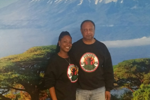 Elders and cofounders Tamu (left) and Hekuma Kanyama standing in front of a Mt. Kilimanjaro mural on the walls of Café ULU.