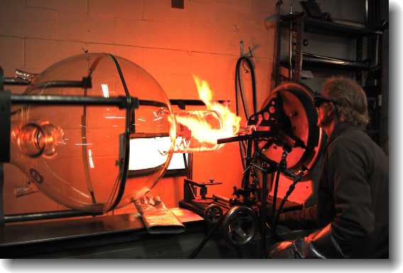 Man making a very large glass beaker.