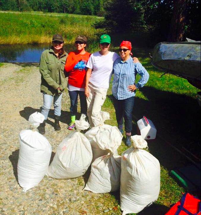 Four women standing in front of five large white bags of wild rice.