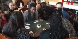 People sitting around a table, playing the card game Loud and Proud.