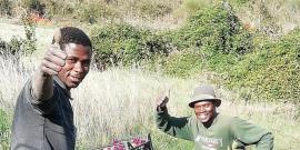 Two men with crates full of vegetables.