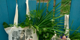 Two canvas shopping bags full of greens and flowers.