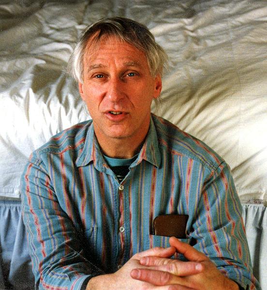 Man looking straight ahead with hands clasped.