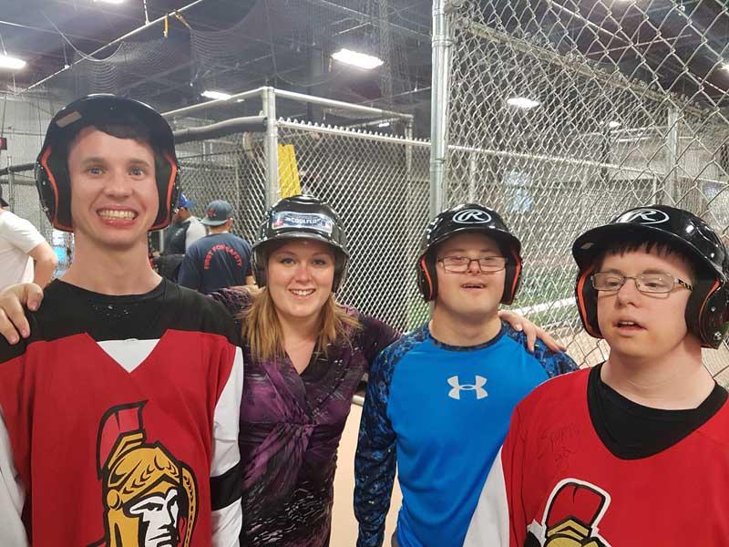 Developmental Services Worker Co-operative member with three clients at a batting cage.