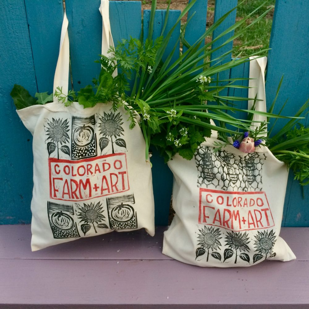 Two canvas shopping bags full of greens and flowers.