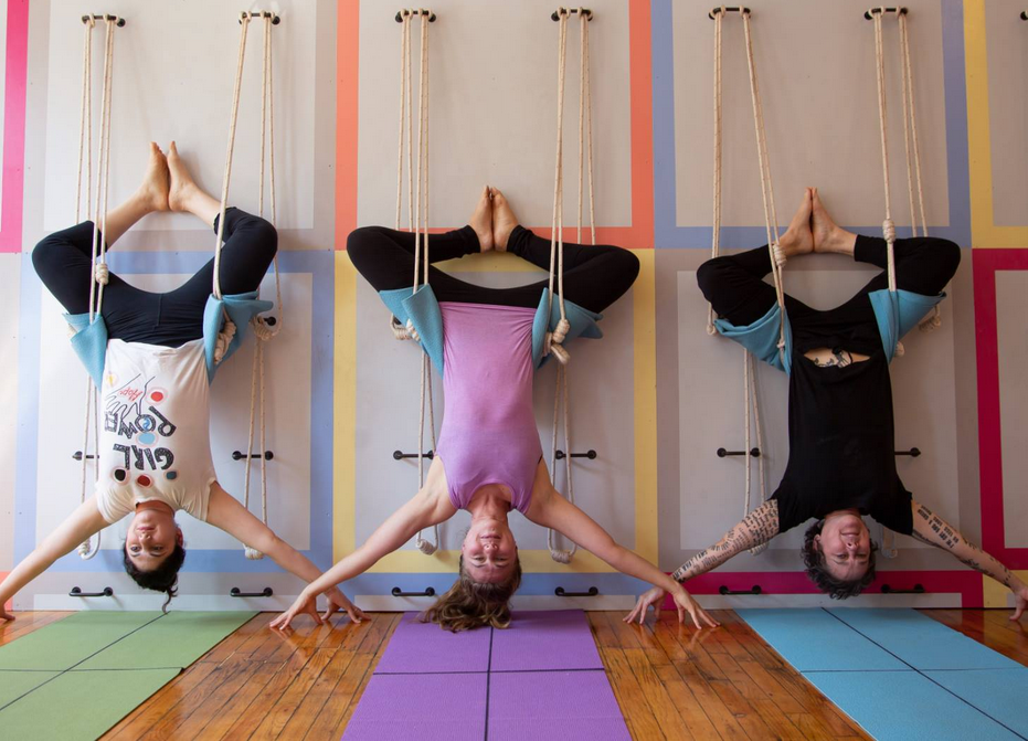 Three women hanging upside down in the Samamkaya Yoga Collective studio.