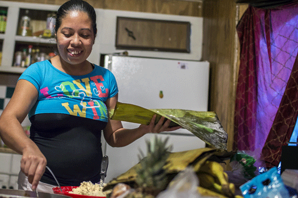 At home in her kitchen, Elideth prepares tamales. She wraps both the masa paste and the chicken and mole sauce in a corn husk and then steams it. Photo by Martin Do Nascimento