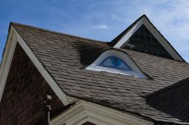 Gable on the roof of a house painted to look like an eye.