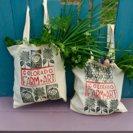 Two canvas shopping bags full of greens and flowers.