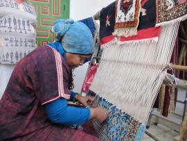 Woman making a carpet on a hand loom.