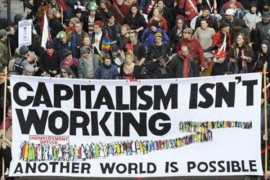 Protesters from Occupy Wall Street holding a banner that reads "capitalism isn't working."