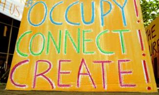 Large Cardboard protes sign reading "OCCUPY! CONNECT! CREATE!"
