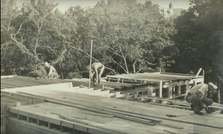 Historical photo of three men constructing a house for a housing cooperative.