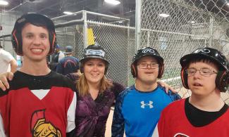 Developmental Services Worker Co-operative member with three clients at a batting cage.