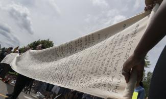 Protesters hold a scroll listing names of people killed by police in Minnesota.