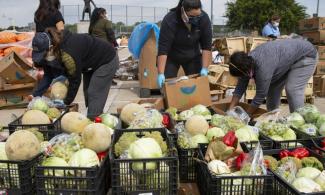 Volunteers with the Harvest Project Food Rescue help prepare food to be distributed at Jaycee Zaragoza Park in Dallas, TX.
