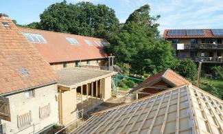 North bar, dance hall and straw bale house behind the sauna and unfinished shed roof (Ecovillage Sieben Linden). Photo by Herbst77regen, via Wikimedia Commons